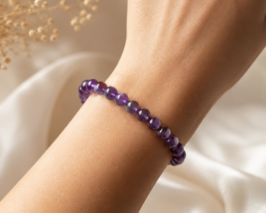 Bracelet en Améthyste porté au poignet, avec perles violettes en pierre naturelle dans une ambiance douce et lumineuse.