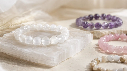 Bracelet en Sélénite blanche translucide aux reflets satinés, posé sur une plaque de sélénite avec des bracelets en pierres naturelles à recharger, lithothérapie purification