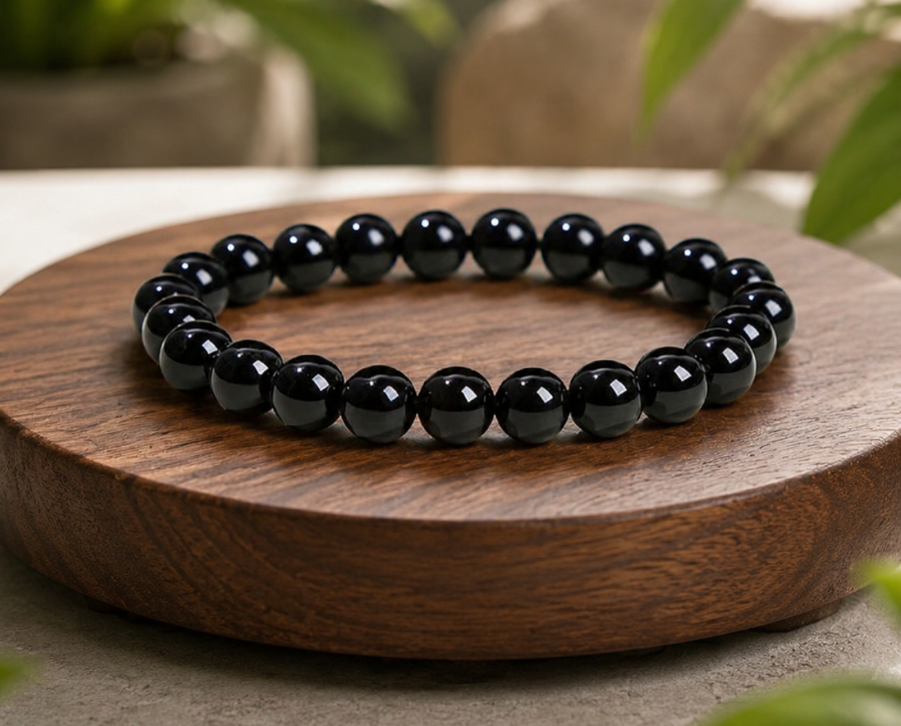 Bracelet en Agate naturelle traitée noire sur un socle en bois, avec perles brillantes dans un décor végétal.