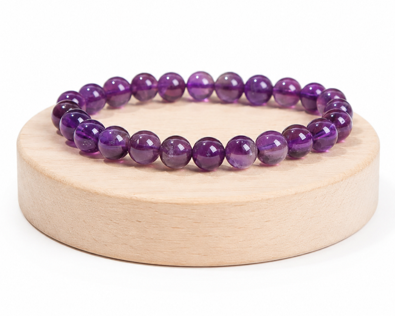 Bracelet en Améthyste présenté sur un socle en bois fond blanc, avec perles violettes en pierre naturelle aux reflets brillants.