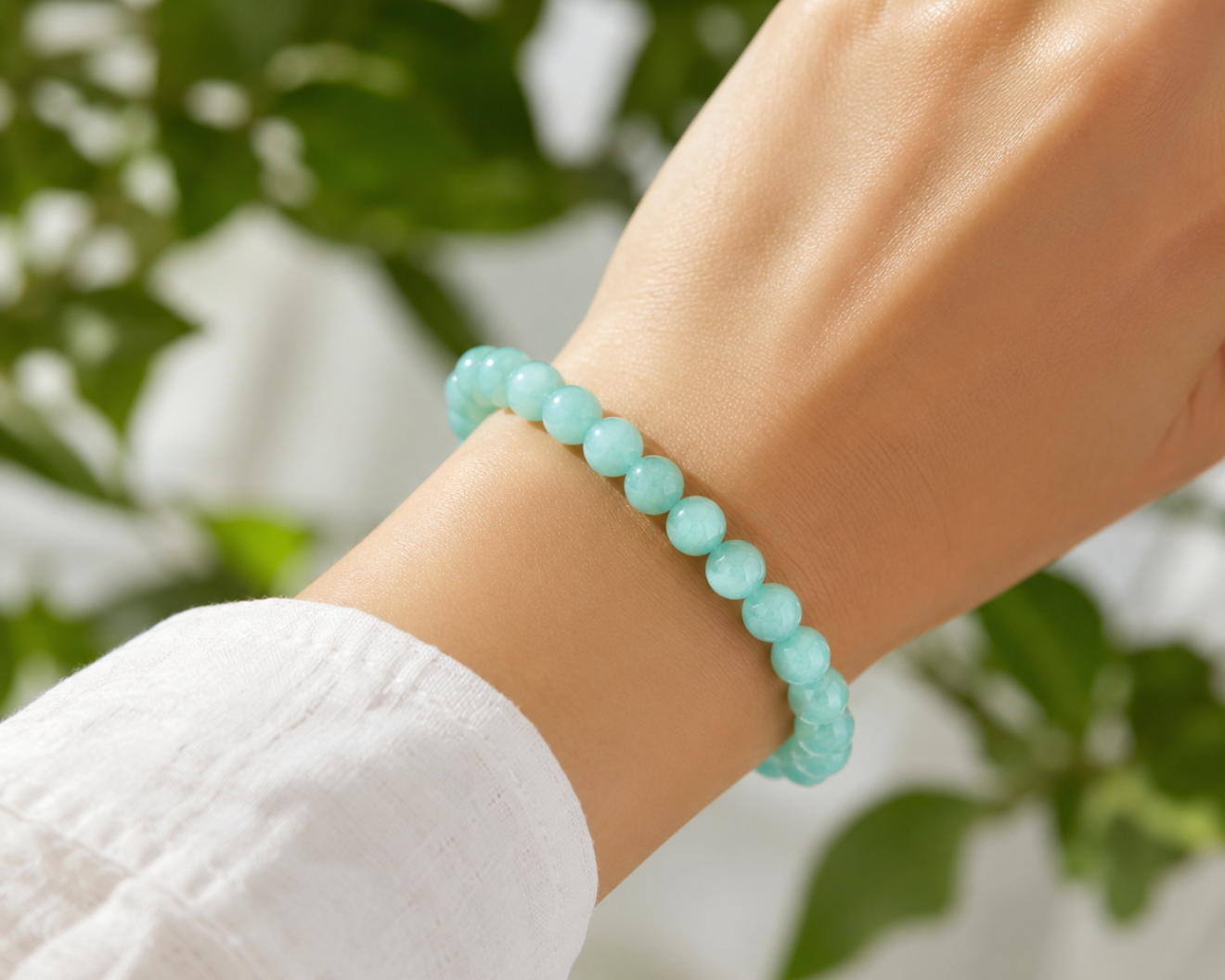 Bracelet en Aventurine verte porté au poignet, avec perles vert clair en pierre naturelle devant un décor végétal doux.