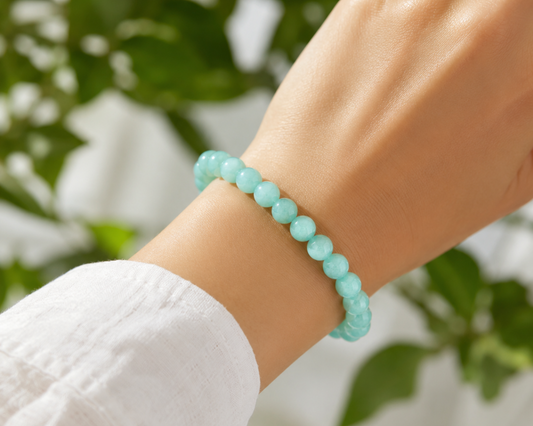 Bracelet en Aventurine verte porté au poignet, avec perles vert clair en pierre naturelle devant un décor végétal doux.