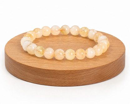 Bracelet en Citrine chauffée issue d’Améthyste naturelle présenté sur un socle en bois, avec perles jaune doré sur fond blanc.
