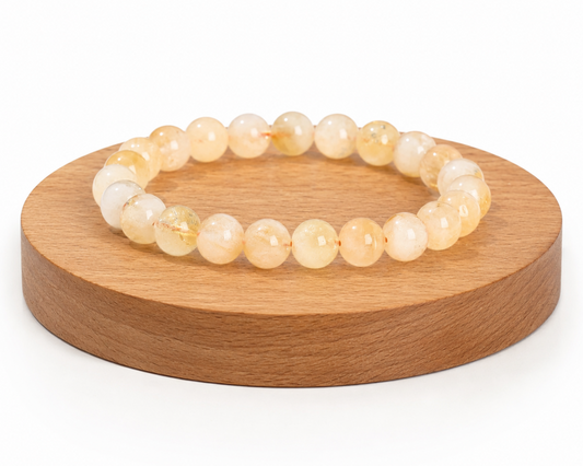 Bracelet en Citrine chauffée issue d’Améthyste naturelle présenté sur un socle en bois, avec perles jaune doré sur fond blanc.