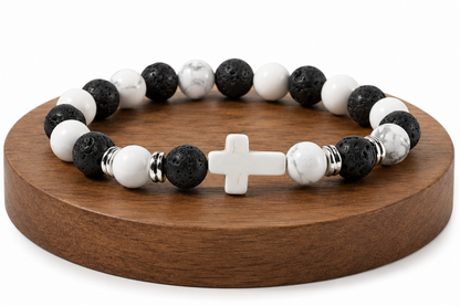 Bracelet Howlite et Pierre de Lave avec croix blanche présenté sur un socle en bois, avec perles blanches veinées, perles noires texturées et détails métal.