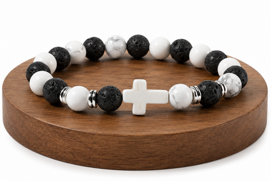 Bracelet Howlite et Pierre de Lave avec croix blanche présenté sur un socle en bois, avec perles blanches veinées, perles noires texturées et détails métal.