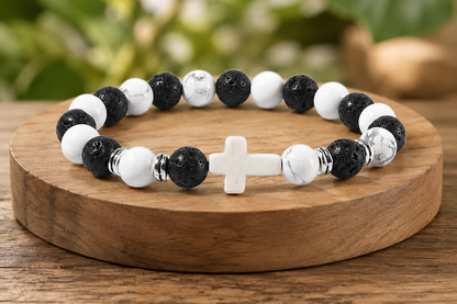 Bracelet Howlite et Pierre de Lave avec croix blanche présenté sur un socle en bois, avec perles blanches veinées, perles noires texturées et détails métal.