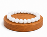 Bracelet en Jade Blanc naturel présenté sur un socle en bois fond blanc, avec perles blanches lumineuses.