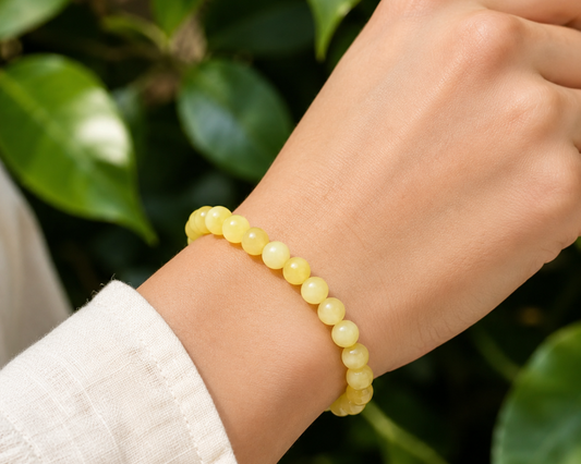 Bracelet en Serpentinite naturelle teintée jaune, appelée Jade Citron, porté au poignet dans un décor végétal.