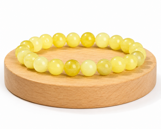 Bracelet en Serpentinite naturelle teintée jaune, appelée Jade Citron, présenté sur un socle en bois fond blanc.