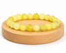 Bracelet en Serpentinite naturelle teintée jaune, appelée Jade Citron, présenté sur un socle en bois fond blanc.
