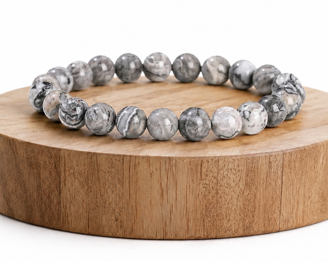 Bracelet en Jaspe Picasso présenté sur un socle en bois fond blanc, avec perles grises en pierre naturelle aux motifs marbrés.