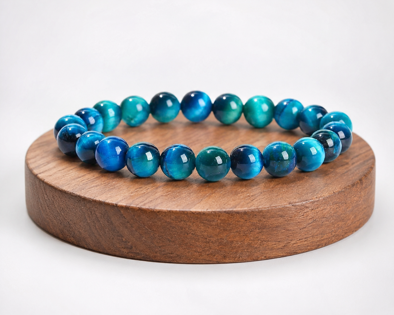 Bracelet en Œil de Faucon présenté sur un socle en bois fond clair, avec perles bleues aux reflets chatoyants.