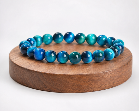 Bracelet en Œil de Faucon présenté sur un socle en bois fond clair, avec perles bleues aux reflets chatoyants.