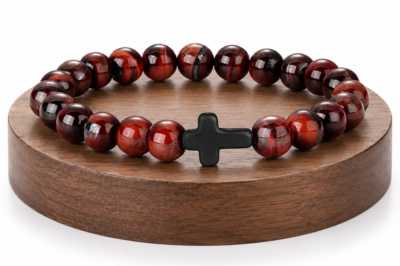 Bracelet en Œil de Taureau avec croix noire présenté sur un socle en bois fond blanc, avec perles brunes et rouges aux reflets brillants.