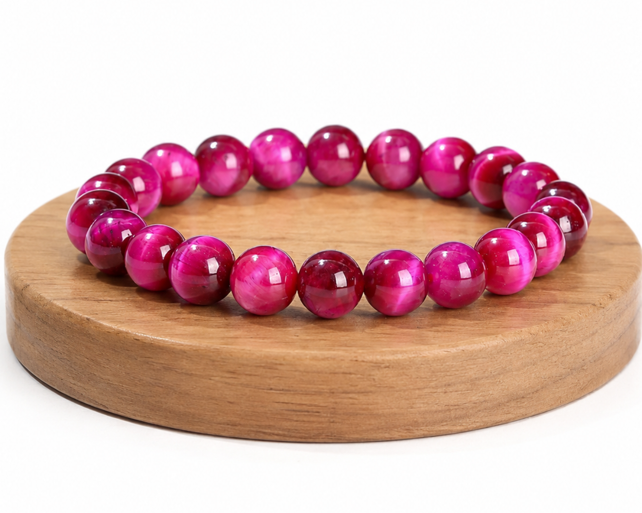 Bracelet en Œil de Tigre traité fuchsia présenté sur un socle en bois, avec perles chatoyantes sur fond blanc.