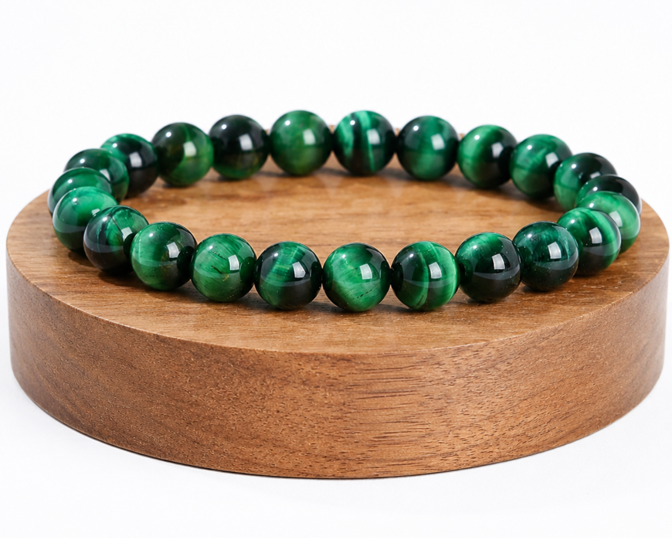 Bracelet en Œil de Tigre traité vert présenté sur un socle en bois, avec perles chatoyantes sur fond blanc.