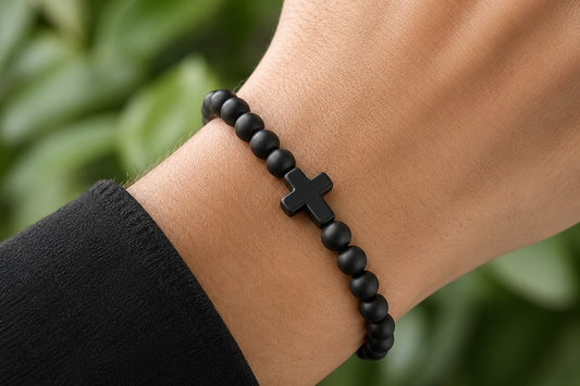 Bracelet en Onyx noir mat porté au poignet, avec perles noires mates devant un décor végétal.