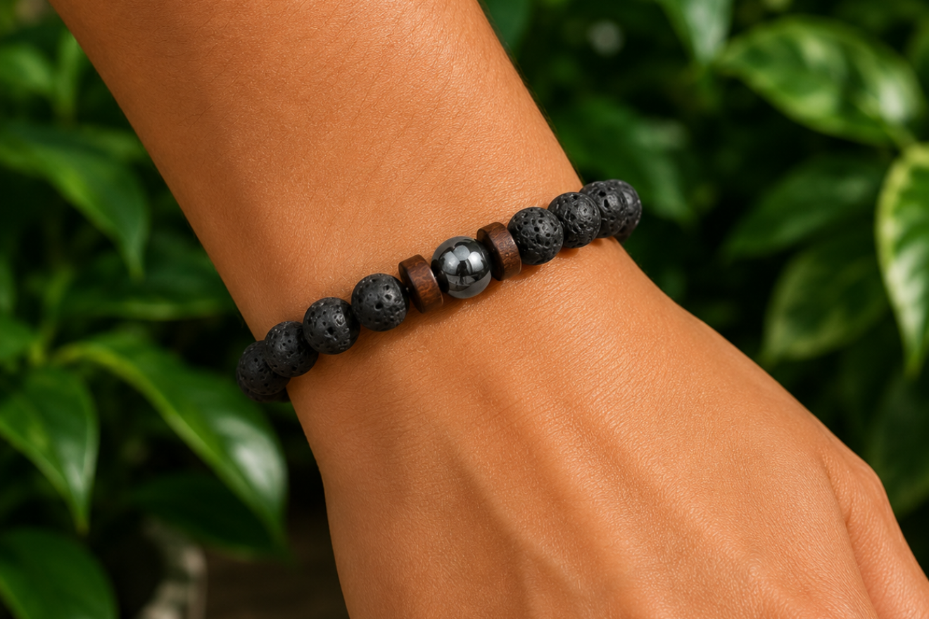 Bracelet homme en Pierre de Lave et bois porté au poignet, avec perles noires texturées et perles bois dans un décor végétal.