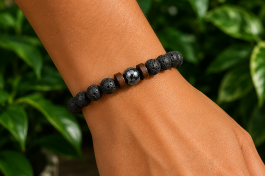 Bracelet homme en Pierre de Lave et bois porté au poignet, avec perles noires texturées et perles bois dans un décor végétal.