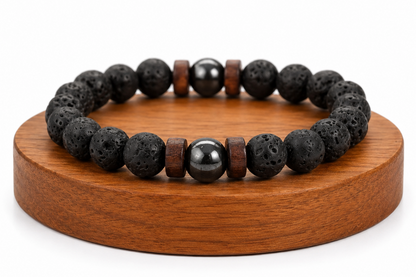 Bracelet homme en Pierre de Lave et bois présenté sur un socle en bois fond blanc, avec perles noires texturées et perles bois.