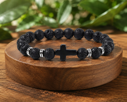 Bracelet en Pierre de Lave avec croix noire et perles métal présenté sur un socle en bois, avec perles noires texturées dans un décor végétal.