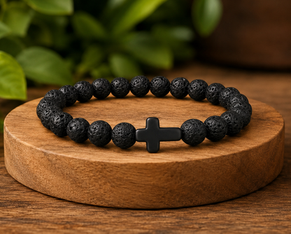 Bracelet en Pierre de Lave avec croix noire présenté sur un socle en bois, avec perles noires texturées dans un décor végétal.