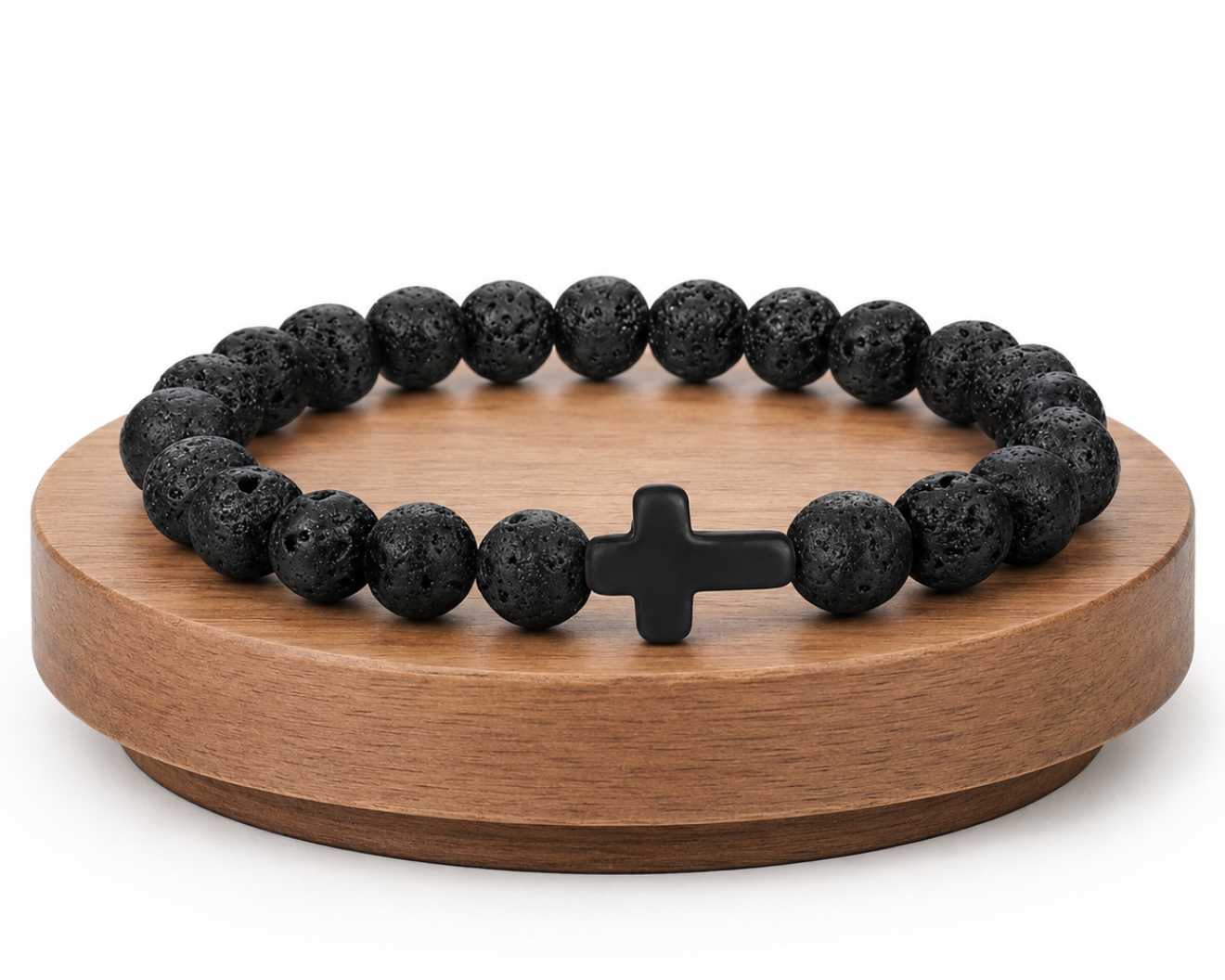 Bracelet en Pierre de Lave avec croix noire présenté sur un socle en bois fond blanc, avec perles noires texturées.