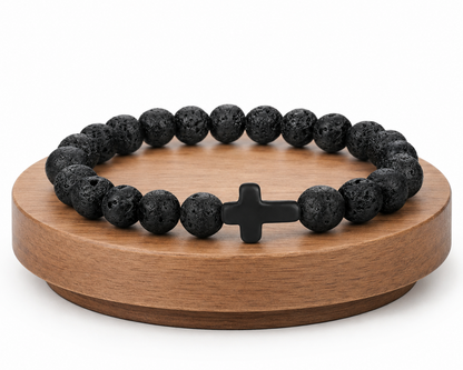 Bracelet en Pierre de Lave avec croix noire présenté sur un socle en bois fond blanc, avec perles noires texturées.