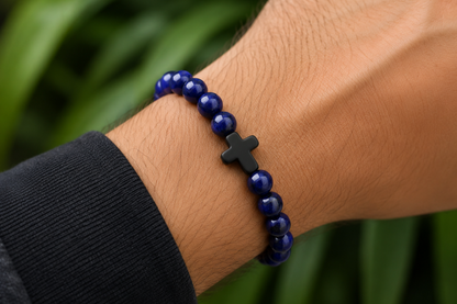 Bracelet en Sodalite porté au poignet, avec perles bleues en pierre naturelle devant un décor végétal.