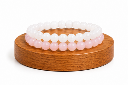 Bracelets Quartz Rose et Jade Blanc présentés sur un socle en bois fond blanc, avec perles rose pâle et perles blanches lumineuses.